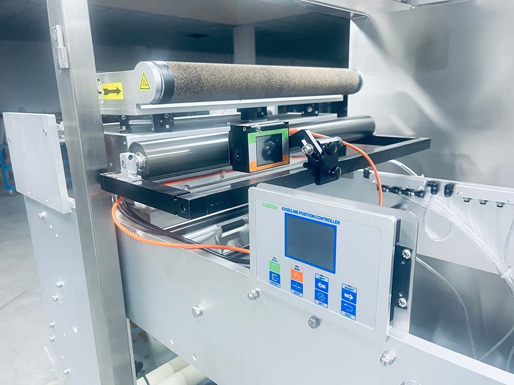 Edge line position controller and film tension rollers on an HMK series horizontal flow wrap line.