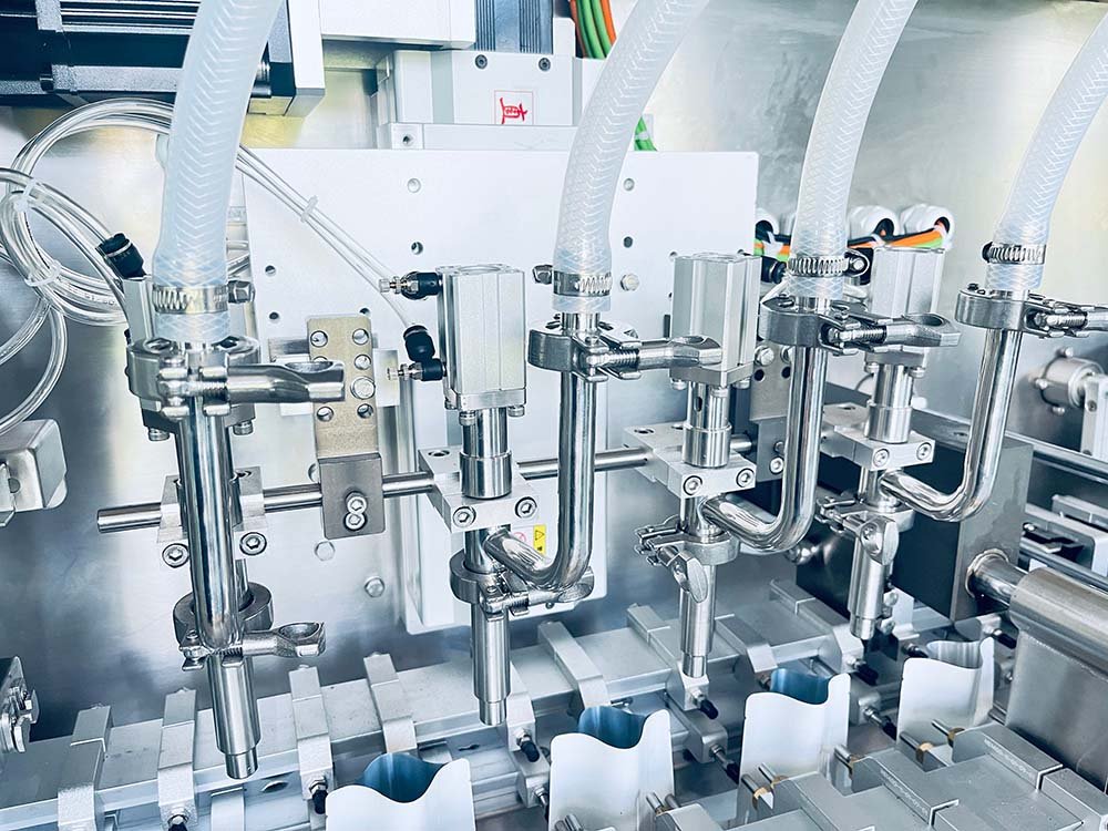 Multi-head liquid filling nozzles with food-contact compliant materials on an HMK horizontal packaging machine line.