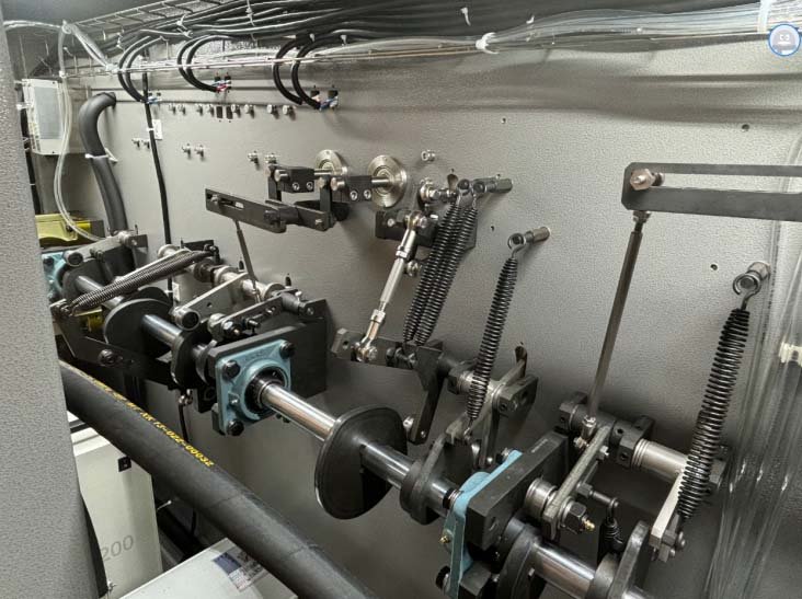 Pure mechanical cam and shaft drive system with heavy tension springs inside a pouch packaging machine.