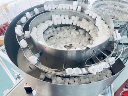 Vibratory bowl spout and cap feeder for a side-spout pouch system
